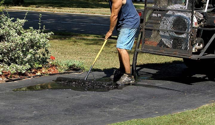 Image of a man applying asphalt sealer
