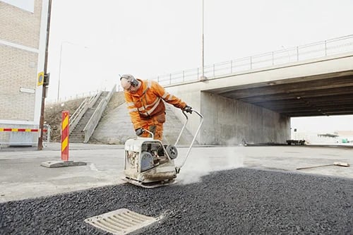 Manual worker laying asphalt at road construction site