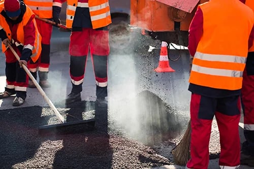 Worker leveling fresh asphalt on a road construction site